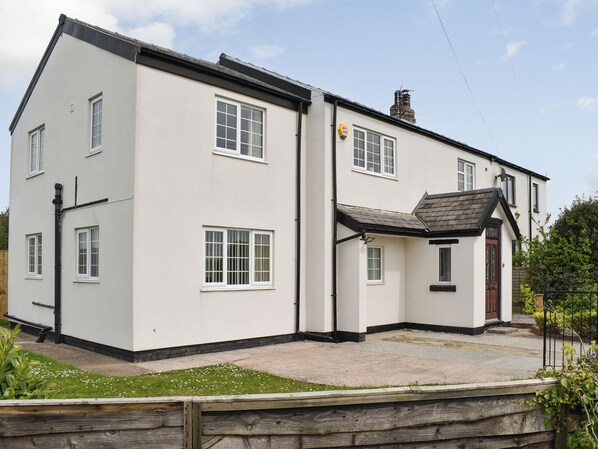 A two-story house with a white exterior, multiple windows, a small porch, and a chimney. - 5 bedroom accommodation in Warton, near Lytham (Warton, near Lytham)