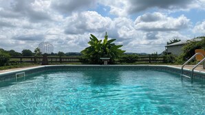 A clear swimming pool with a wooden deck and a metal ladder.