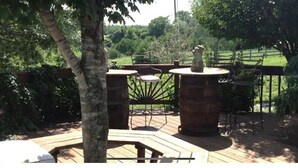 An outdoor patio area with a wooden deck, a metal chair, and a stone table.