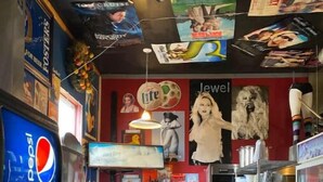 A restaurant interior with a counter, seating area, and various posters and decorations on the walls.