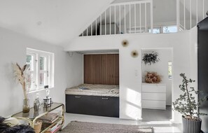 Relax in this spacious bedroom with a loft-style design, featuring a large bed and bench with storage.