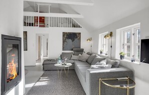 Relax in this spacious living room with a mezzanine level, featuring a comfortable sofa, flat-screen TV, and a fireplace.