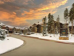 Escape to a serene winter wonderland amidst rustic buildings and snow-covered trees.