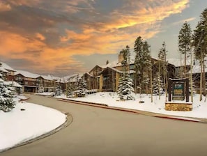 Escape to a serene winter wonderland amidst rustic buildings and snow-covered trees.