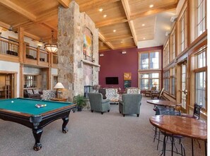 Relax in a spacious lounge area with a pool table, comfortable seating, and a fireplace.