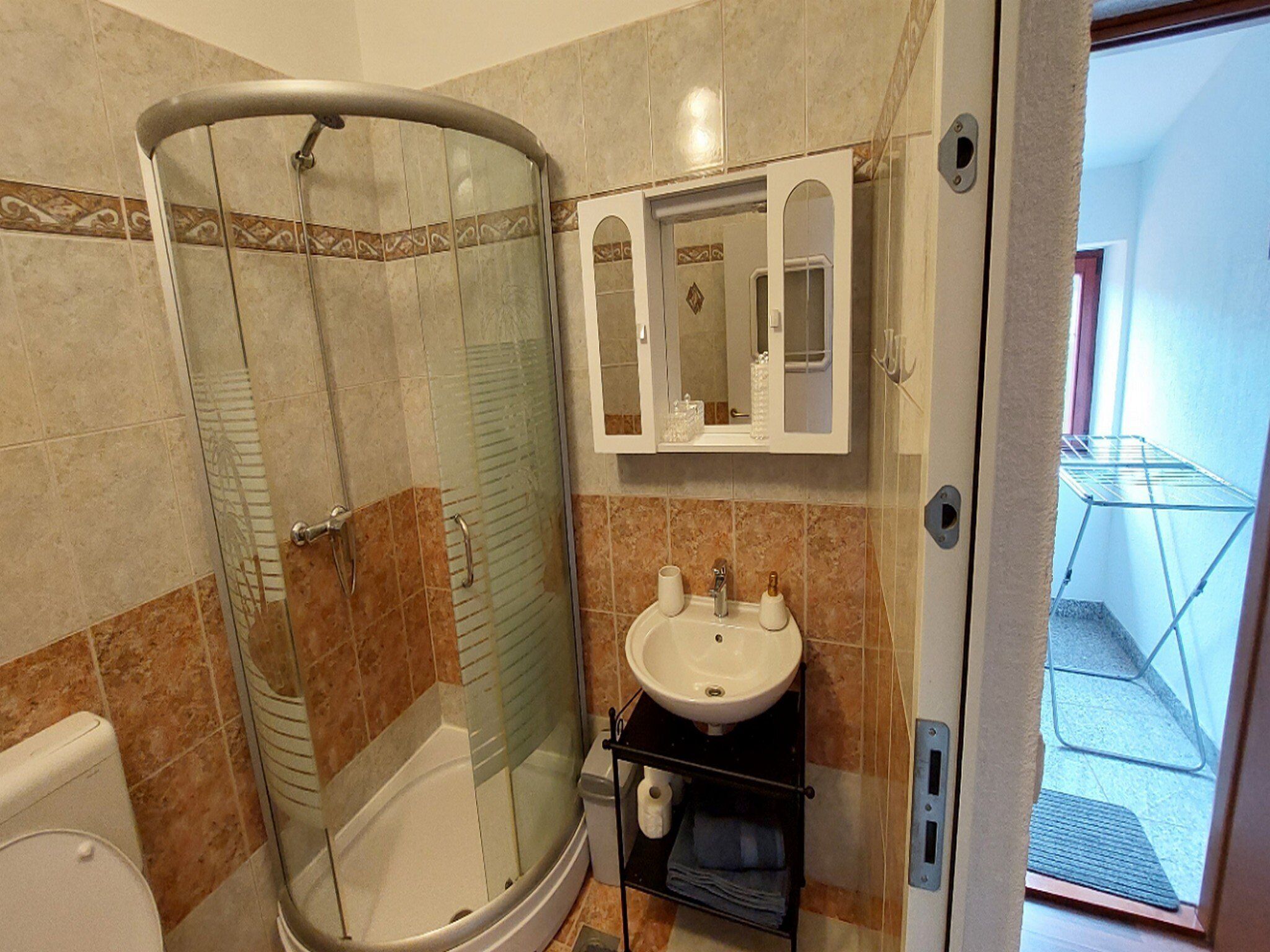 Ein Badezimmer mit Duschkabine, Waschbecken und Spiegel.