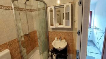 Ein Badezimmer mit Duschkabine, Waschbecken und Spiegel.
