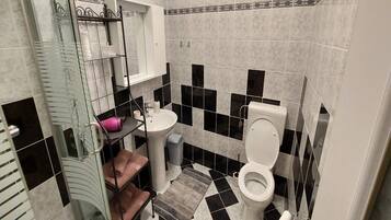 A bathroom with a black and white checkered floor, a white sink, a toilet, and a glass shower enclosure.