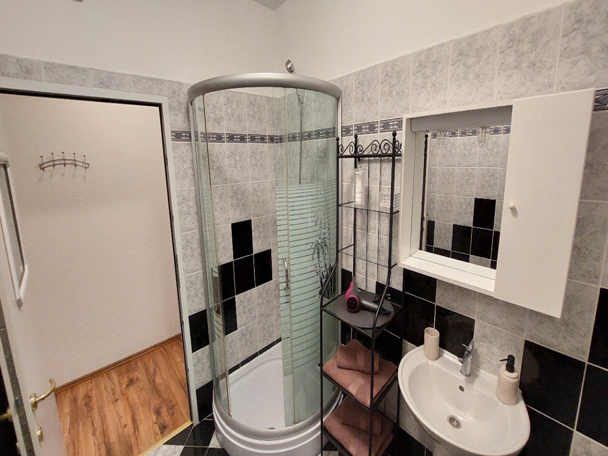 A bathroom with a glass-enclosed shower, a white sink, and a mirror above the sink.