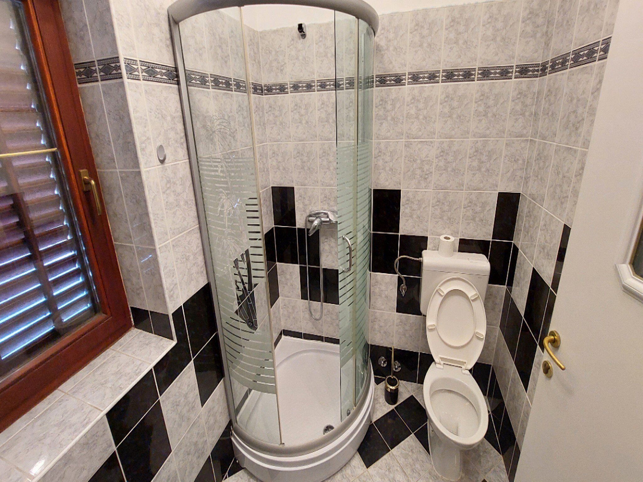 Un baño con ducha de vidrio, inodoro y lavamanos.