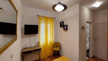 Una habitación con cama, escritorio, silla, televisor y lavadora.