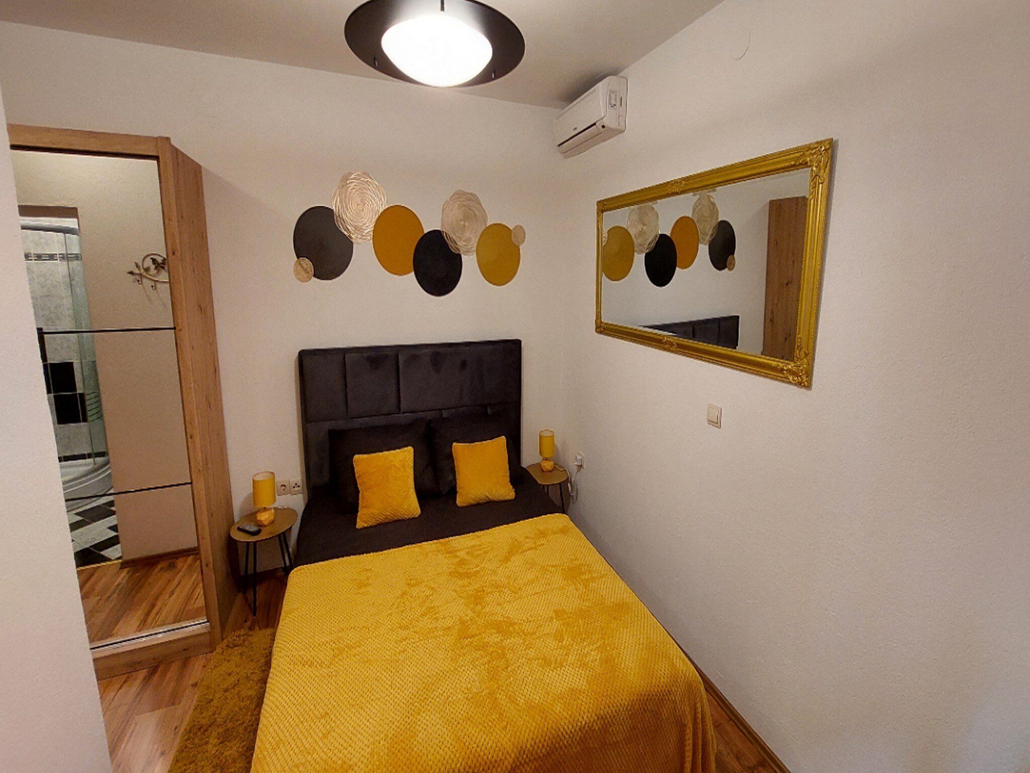 Un dormitorio con cama, espejo y decoración en la pared.