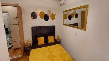 Un dormitorio con cama, espejo y decoración en la pared.