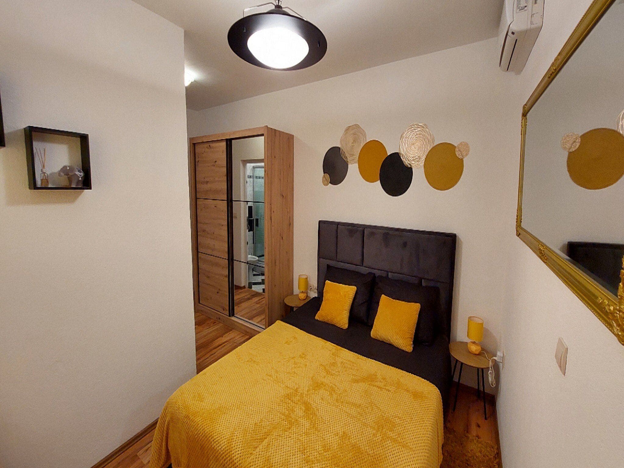 A bedroom with a bed, bedside tables, a mirror, and a wall with circular decorations.