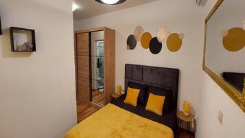 A bedroom with a bed, bedside tables, a mirror, and a wall with circular decorations.