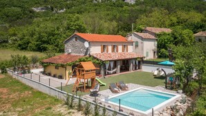 Eine Villa mit Swimmingpool, einer Holzspielanlage und einem kleinen Garten.