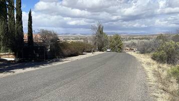 A paved road curving through a rural landscape with sparse vegetation and distant buildings.