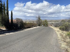 A paved road curving through a rural landscape with sparse vegetation and distant buildings. - Verde River Hilltop Gem - Tranquil, artistic and close to everything (Cottonwood)