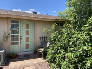 A house with a green door, a small porch with a chair, and a large tree in the foreground. - Verde River Hilltop Gem - Tranquil, artistic and close to everything (Cottonwood)