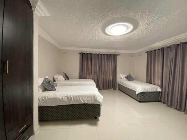 Habitación de hotel con dos camas, un armario y una lámpara en el techo.
