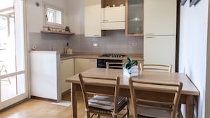 Una cocina con una mesa de comedor, sillas, estufa y armarios.