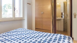 Un dormitorio con cama, armario y baño a la vista, accesible a través de una puerta abierta.
