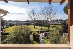 A view from a balcony overlooking a green landscape with trees and a distant town.