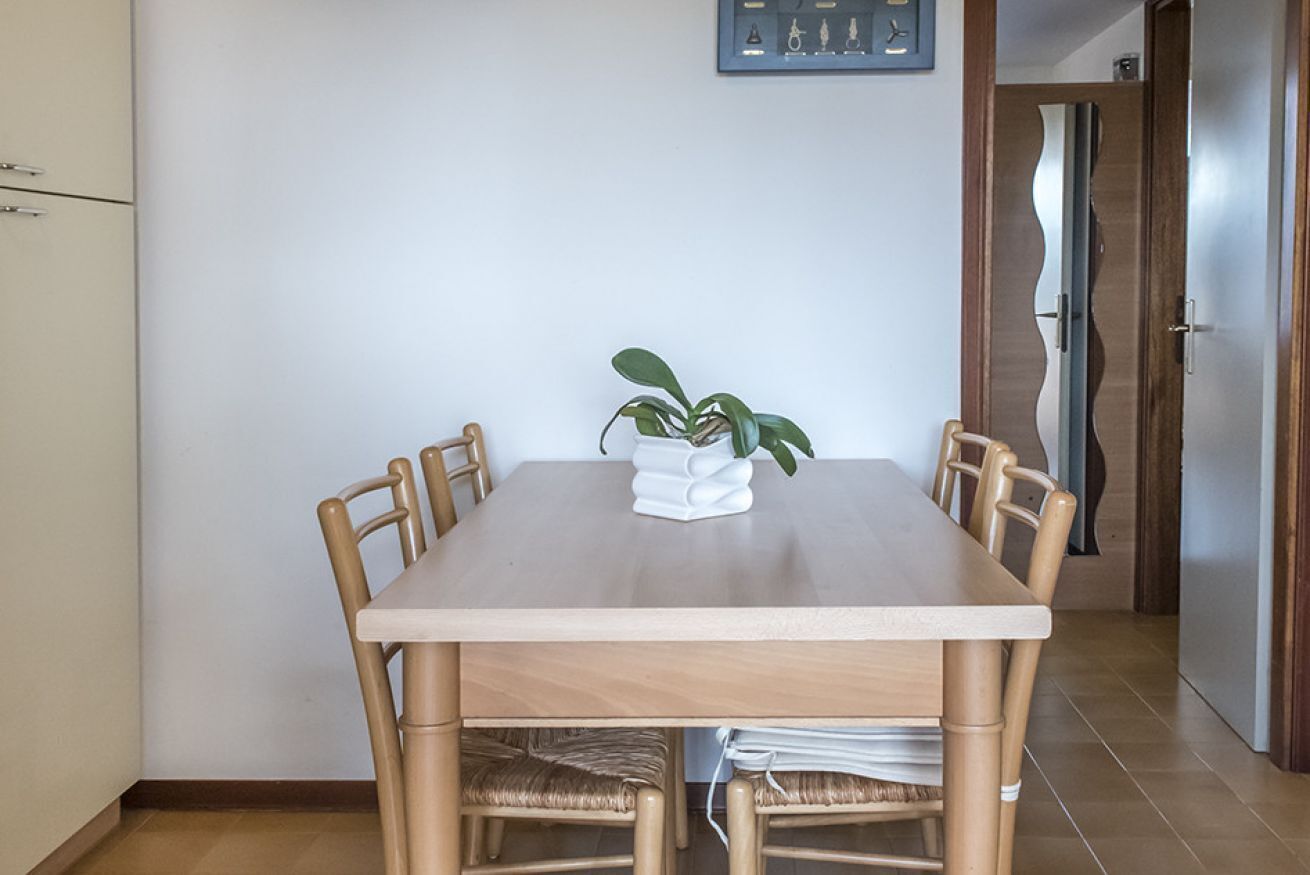 Un coin repas avec une table et des chaises, une plante en pot et une horloge au mur.