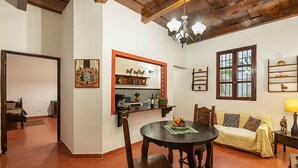 A dining area with a round table, chairs, and a sofa. There is a kitchen area with a counter and shelves. - Casita Tumbergia (Antigua Guatemala)