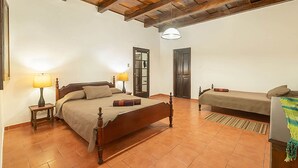 A bedroom with two beds, wooden beams on the ceiling, and tiled flooring. - Casita Tumbergia (Antigua Guatemala)