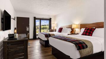 Habitación de hotel con dos camas, un escritorio de madera y vistas a zonas verdes.