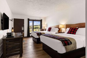Ein Hotelzimmer mit zwei Betten, einem Holztisch und Blick auf Grünflächen.