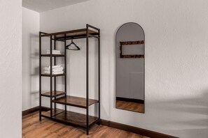Ein Eckzimmer mit Holzboden, einem Metallregal mit Handtüchern und einem Spiegel mit Holzrahmen.