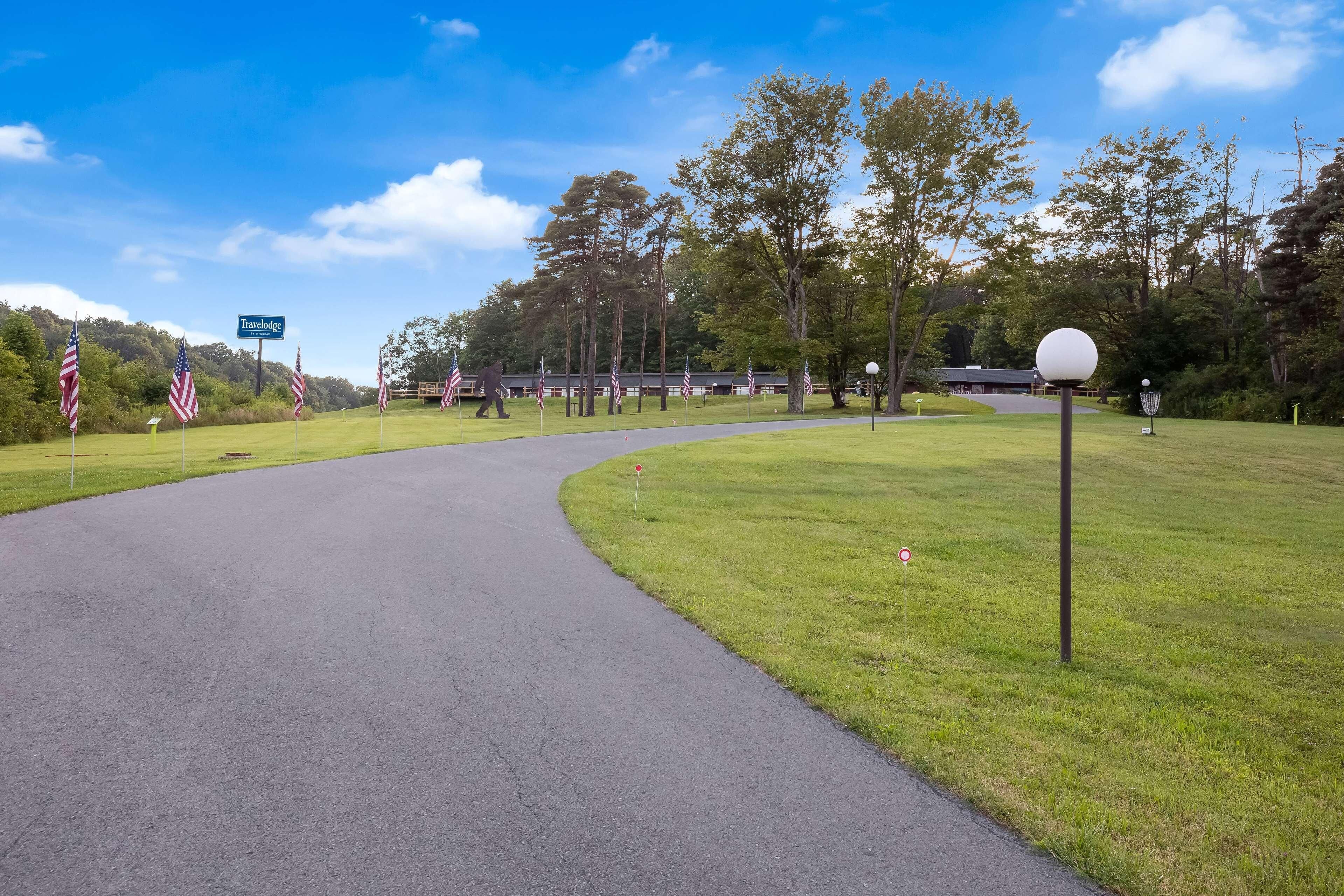 A golf course with a curved path, American flags, and a sign reading "Travelogue."