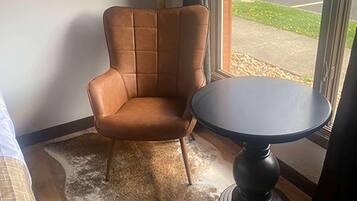 Una habitación de esquina con un sillón de cuero marrón y una mesa redonda.