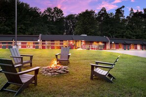 Un chalet doté d’un foyer extérieur et de chaises Adirondack dans la cour.