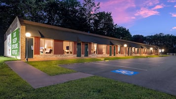 A motel with multiple rooms, a parking lot, and a grassy area.