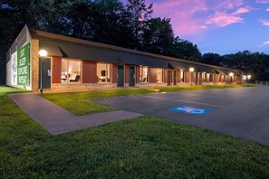 Ein Motel mit mehreren Zimmern, einem Parkplatz und einer Grünfläche.