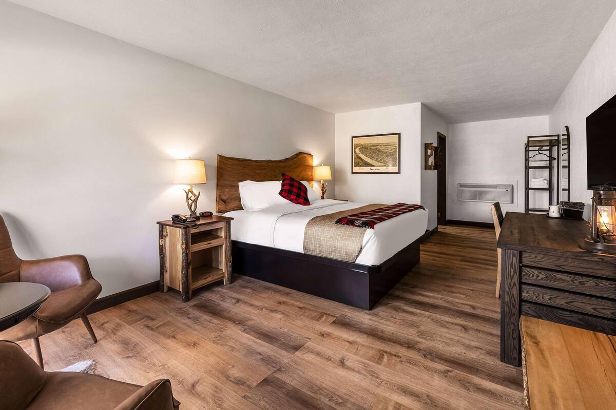 Une chambre d’hôtel avec un lit, un bureau, une chaise, une lampe et un tableau au mur.