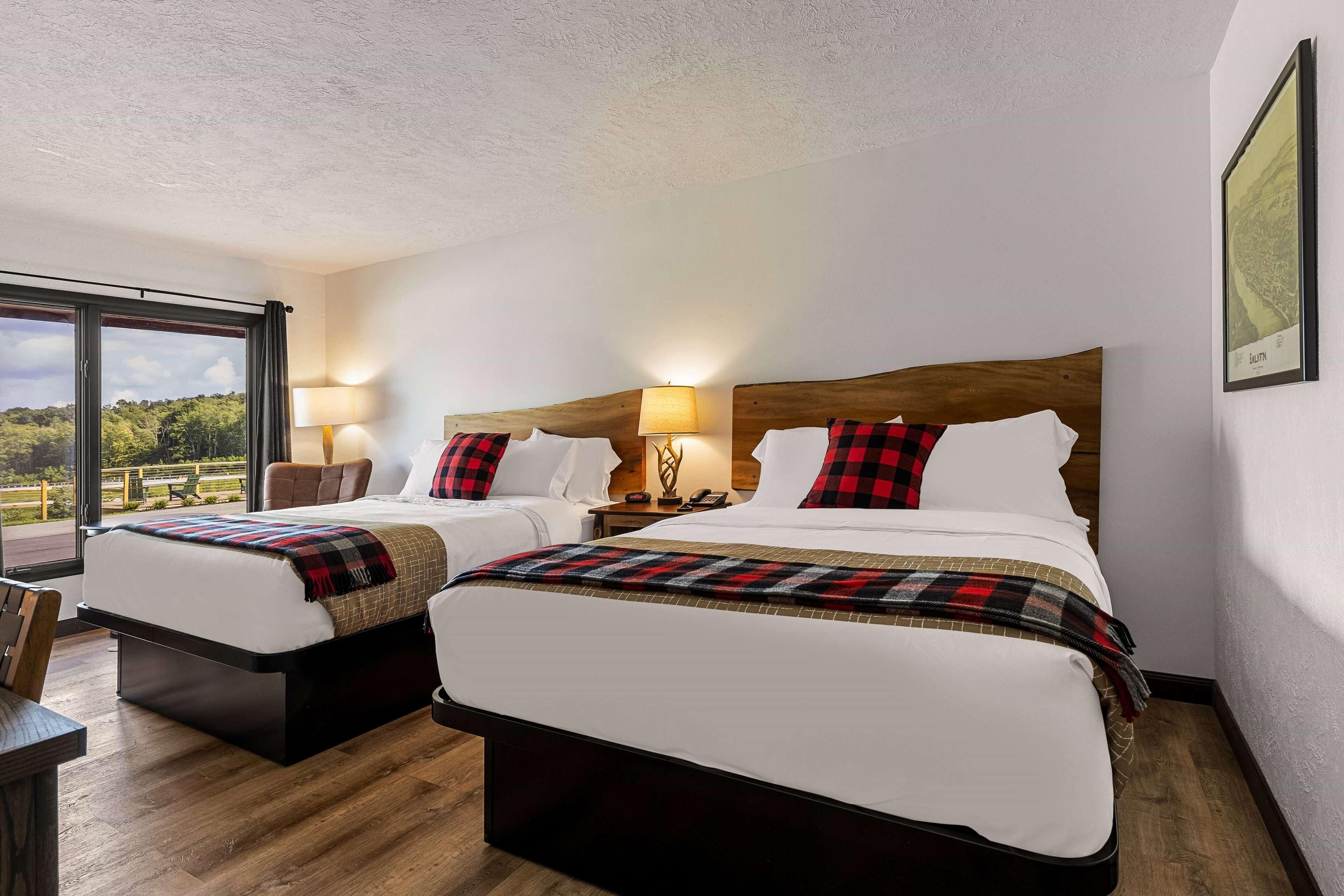 Habitación de hotel con dos camas, un ventanal grande y vistas al exterior.