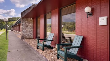 A building with red exterior walls, large windows, and outdoor seating with Adirondack chairs.