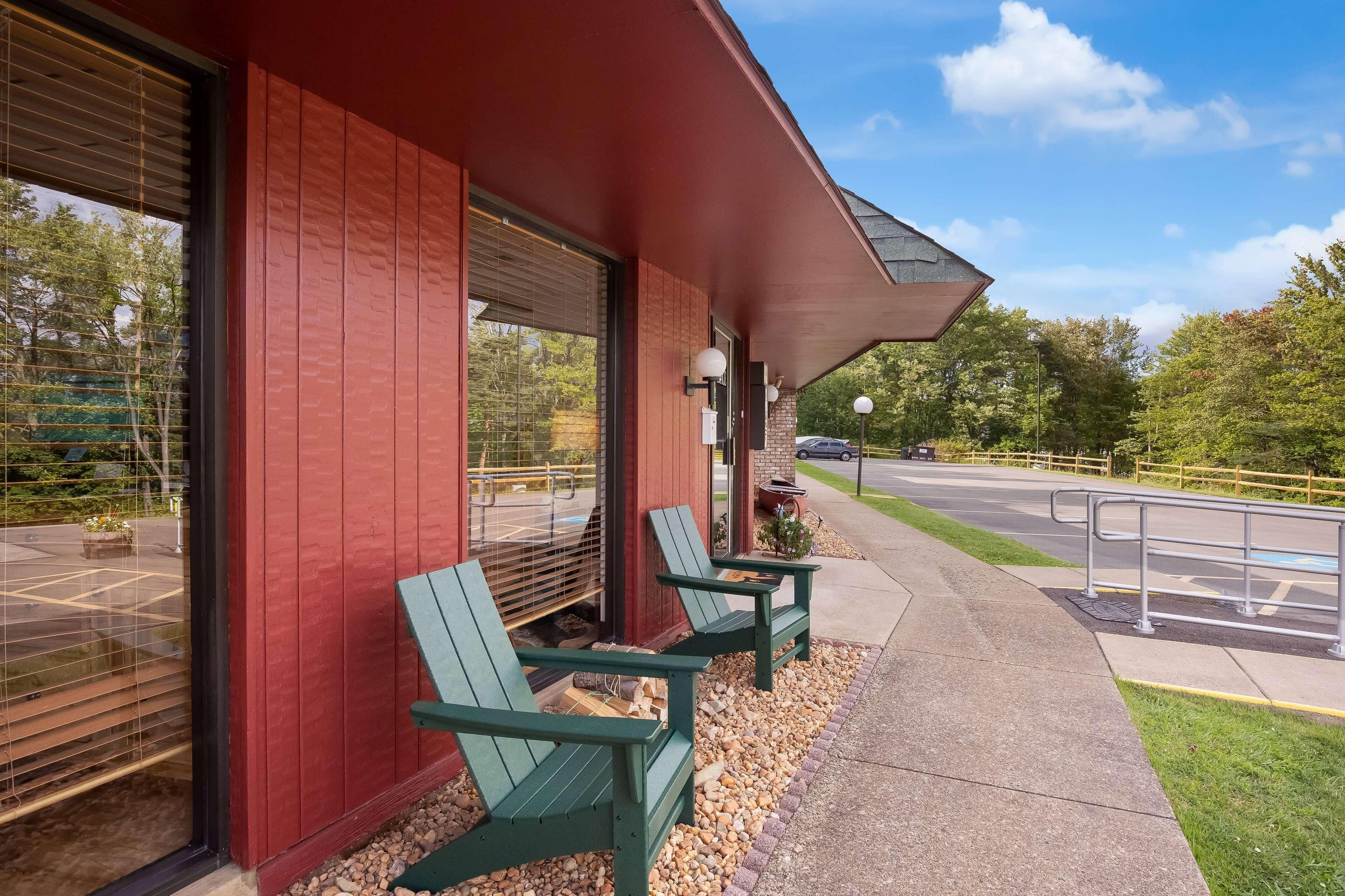 A building with a red exterior, two green Adirondack chairs, and a parking lot in the background.