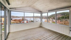 A covered balcony with large windows offering a view of a lake and surrounding landscape. - Cozy home in Uddevalla (Uddevalla)
