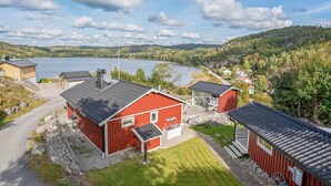 A red building with a small porch and a water pump, surrounded by a gravel path and a grassy area. - Cozy home in Uddevalla (Uddevalla)