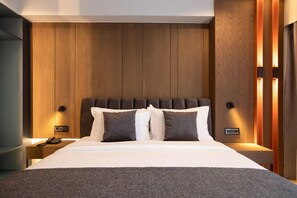 A modern bedroom with a wooden headboard, a large bed with white and dark gray bedding, and bedside tables with lamps. - Elisa Hotel Tirana Affiliated By Melia (Tirana)