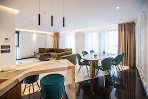 A modern dining area with a marble bar, green upholstered chairs, and a round table. - Elisa Hotel Tirana Affiliated By Melia (Tirana)