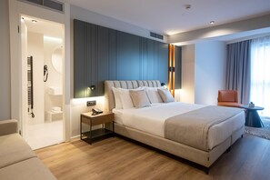 A modern hotel room with a large bed, a bedside table with a phone, a chair, and a small table with a plant. - Elisa Hotel Tirana Affiliated By Melia (Tirana)