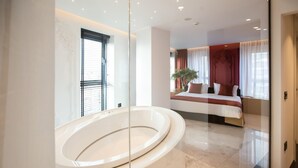 A modern bathroom with a large oval bathtub, a glass-enclosed shower area, and a marble floor. - Elisa Hotel Tirana Affiliated By Melia (Tirana)