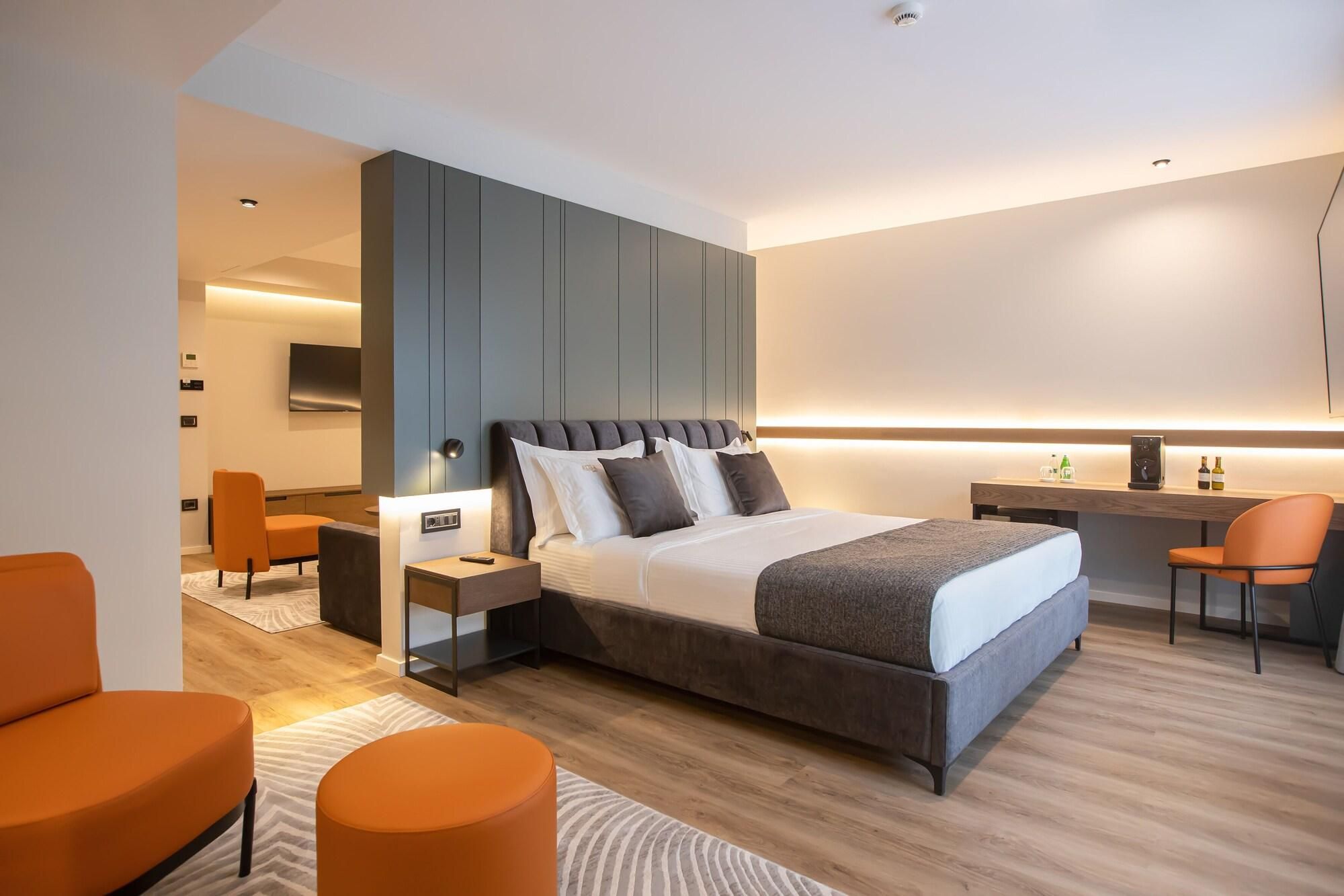 A modern hotel room with a large bed, a desk, and a seating area.