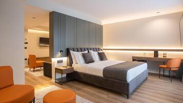 A modern hotel room with a large bed, a desk, and a seating area.